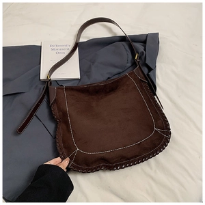 Detail of dark brown suede hobo bag with white stitching and woven leather trim edge