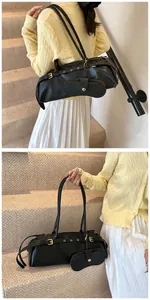 Close-up of black baguette bag featuring adjustable buckle straps and a matching pouch