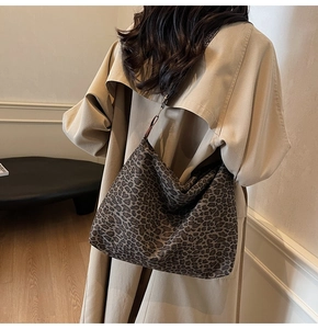 Rear view of a large leopard print tote bag styled with a khaki trench coat in soft light