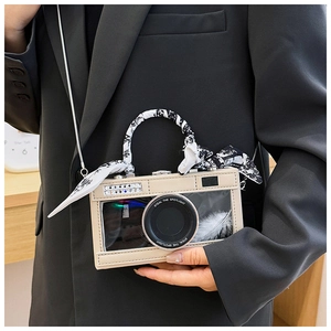 Detail of camera-shaped crossbody bag with floral scarf handle and feather window