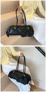 Detailed close-up of a black leather baguette bag with golden buckle and small pouch