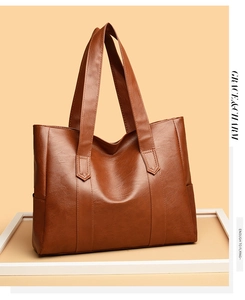 Detailed macro view of brown PU leather texture and shoulder strap on large tote bag