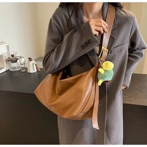 Detail of a large brown tote bag in soft leather with an adjustable strap and turtle charm