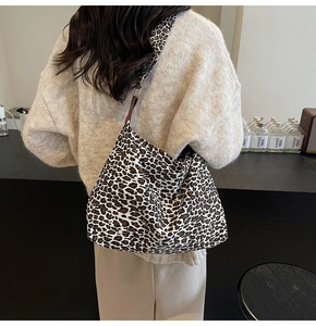 Detailed back view of a large leopard print canvas tote bag worn by a model
