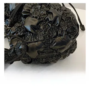 Détail du tissu plissé noir et de la boucle en métal sur la bandoulière du sac