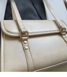 Close-up of beige crossbody bag showing soft leather texture and golden metal buckle
