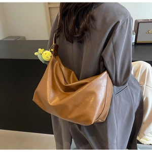 Brown hobo tote bag in soft leather texture with cute plush worm charm on model