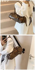 Detail of dark brown baguette bag with unique glasses-shaped front pocket and long strap