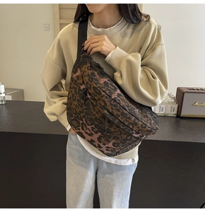 Detail view of a stylish leopard print crossbody chest bag worn by a model in a cafe setting
