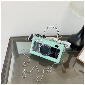 Detail of mint green camera-shaped bag with silk scarf handle and silver chain strap