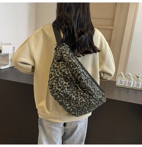 Close-up of leopard print crossbody bag with adjustable strap worn in a cafe setting