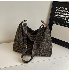 Detailed close-up of leopard print tote bag featuring brown leather strap and gold metal buckle