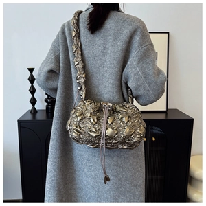 Détail du sac à bandoulière plissé bronze métallique avec cordon sur mannequin en manteau