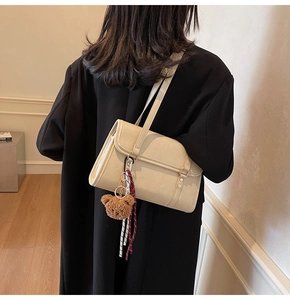 Detail of cream PU leather crossbody bag with brown bear charm and ribbon accent