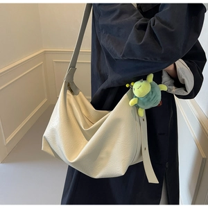 Detail of off-white oversized hobo bag with litchi texture and green turtle plush charm
