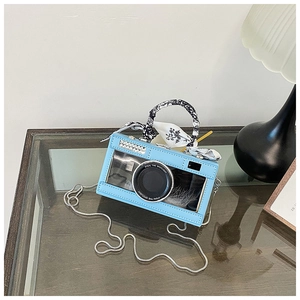 Detail of light blue camera-shaped bag with floral scarf handle and silver chain strap