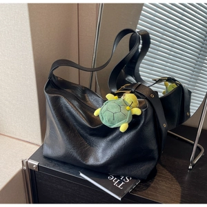 Detail of vintage black tote bag with wide strap and a cute green turtle charm