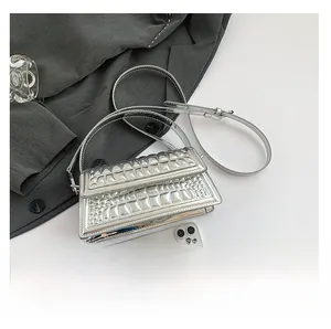 Detailed comparison of silver crocodile texture handbag with a smartphone for size scale