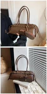 Detail of dark brown baguette bag with metal eyelets and a matching glasses case attachment