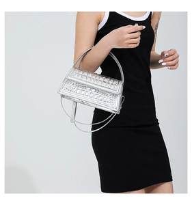 Detail of silver metallic handbag with crocodile texture and studs on black dress