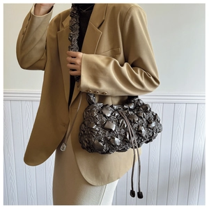 Vue détaillée de la texture plissée métallique et des glands du sac hobo bronze foncé