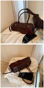 Close-up of a burgundy baguette bag with metal studs and matching mini pouch accessory