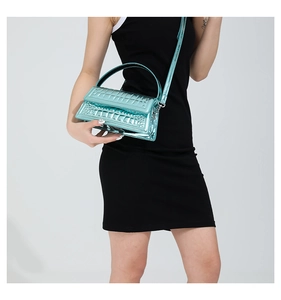Glossy teal blue crocodile-embossed handbag with silver hardware and top handle shown on model
