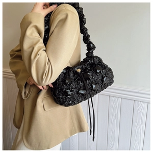 Détail du sac nuage noir avec poignée torsadée et cordon porté avec un blazer de couleur kaki