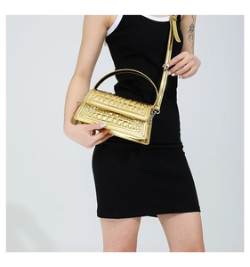 Model wearing a gold crocodile embossed glossy handbag with a detachable shoulder strap