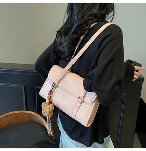 Detail of pink crossbody bag with teddy bear charm and ribbon on model's side