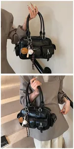 Detail of black glossy PU leather handbag with multiple pockets and sports charms