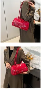 Detail of red faux leather shoulder bag with decorative bow and buckle accents