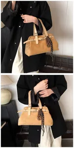 Close-up of khaki suede tote bag with leather straps, metal buckle and decorative charms