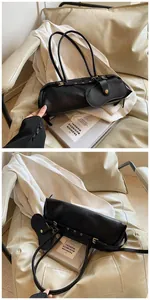 Close-up of black lychee grain baguette bag with mini pouch and metallic buckle on seat