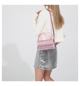 Glossy pink metallic crossbody bag with textured rivet patterns on a fashion model