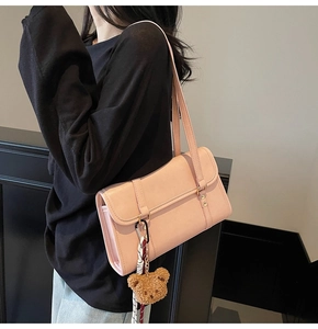 Detailed side view of pink faux leather crossbody bag with cute teddy bear charm