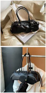 Detail of black textured leather baguette bag with gold hardware and mini pouch charm