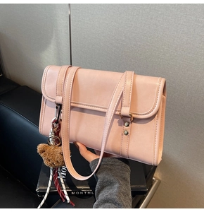 Detailed view of pink crossbody bag with metal buckle and plush bear charm decoration
