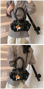 Detail of black patent leather shoulder bag with multi-pockets and baseball charm