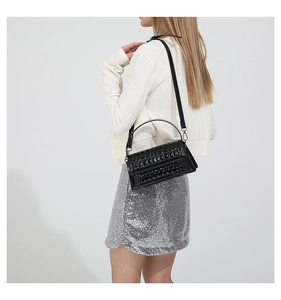 Detail showing glossy crocodile textured leather handbag with metallic silver handle