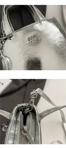 Close-up of silver crossbody bag with pleated texture and metallic logo detailing