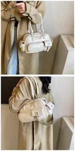 Detail view of cream PU bowling bag featuring multiple pockets and silver hardware zip