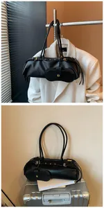 Detail view of black baguette bag in litchi faux leather with elegant gold hardware