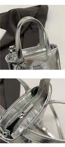 Close-up of silver metallic tote bag featuring pleated texture and zipper closure details