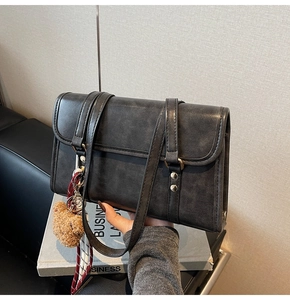 Close-up of charcoal vintage flap bag with metal studs and cute bear charm accessory