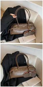 Detail of a brown matte leather baguette bag with vintage gold buckle and a mini pouch