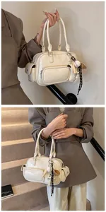 Detail of cream white PU leather bowling bag featuring multiple pockets and baseball charm