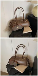 Detail of dark brown baguette bag with decorative straps and small matching hanging pouch