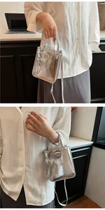 Detail of silver metallic mini tote bag with heart charm and thin shoulder strap