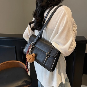 Chic black leather flap crossbody bag for women with cute bear charm and woven strap